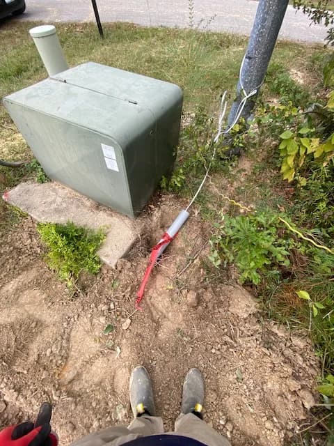 Yard pedestal source connection with red conduit and feeder cable exiting to the trench