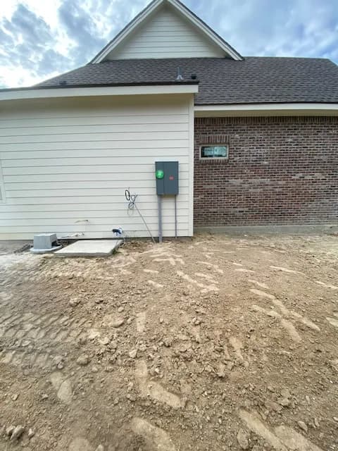 Finished 200A disconnect installation on new-build residence with fresh-graded dirt foreground