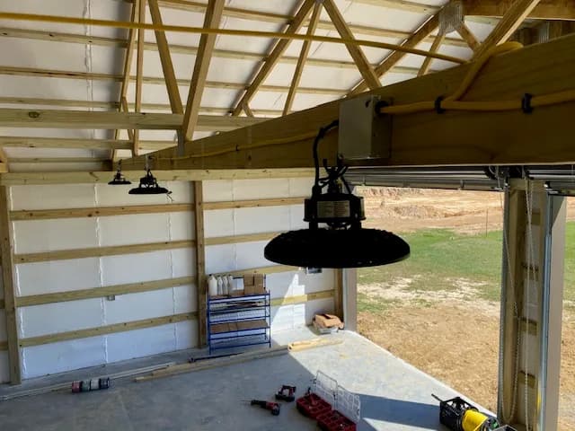Interior shop view with single UFO LED high-bay fixture in focus, ridge framing visible
